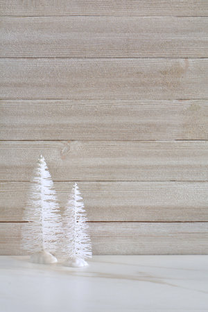 Little white trees on stone table with weathered wood background.  Seasonal decor with room for text in vertical orientation.の写真素材