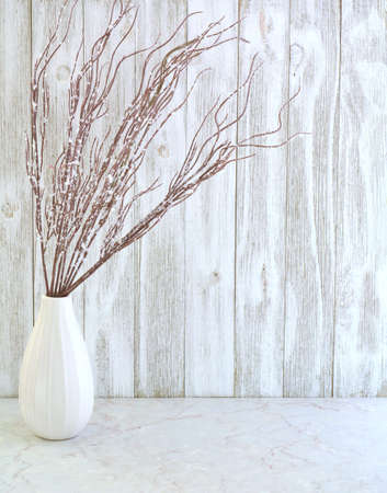 Frosted branches in simple white vase against white weathered boards in vertical format.  Neutral palette still life with room for text.の写真素材