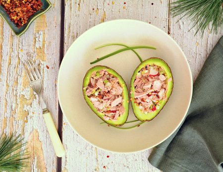 Diet conscious avocado tuna boats with chopped green onion, radish and red pepper flakes for a...