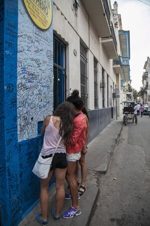 Havana, Cuba - 21 January 2013: A view of the streets of the city with cuban people. Teenagers write something on the wall.のeditorial素材