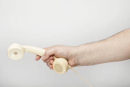 Male hand holds an obsolete telephone receiver, isolated  on the white background.