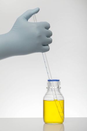 A hand in laboratory gloves mixes chemistry. Liquid in laboratory bottles. Scientific biochemical laboratory. Colorful liquid. Isolated on white background, a group test tubes.の写真素材