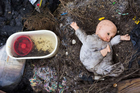 old dirty doll  on a burned ground, traces of the war and fireの写真素材