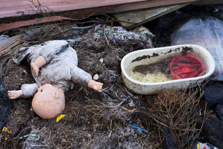 old dirty doll  on a burned ground, traces of the war and fireの写真素材