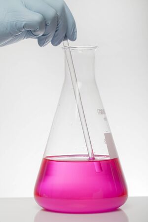 A hand in laboratory gloves mixes chemistry. Liquid in laboratory bottles. Scientific biochemical laboratory. Colorful liquid. Isolated on white background, a group test tubes.の写真素材