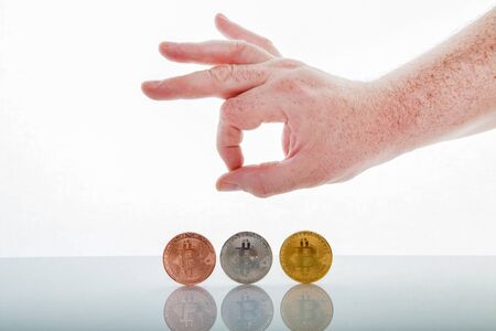 Three bitcoins on white background with hand, Isolated photo.