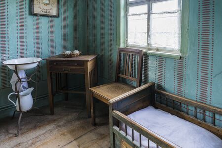 Bad Windsheim, Germany - 16 October 2019: Interior views of a german village house. View of a living room with antique furniture - chair, dresser, wash bowl, cot.のeditorial素材