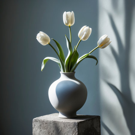An arrangement of tulips is placed in a vase on a stone surface. The background is simple, emphasizing the elegance of the blossoms in a calm still life composition.の素材