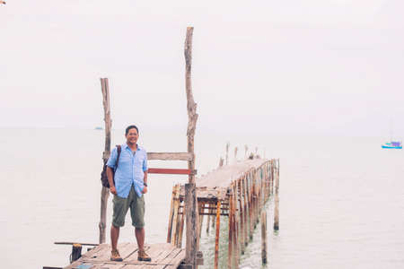 Asian male tourist standing at old wooden bridgeの写真素材