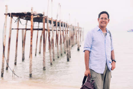 Asian male tourist standing at old wooden bridgeの写真素材