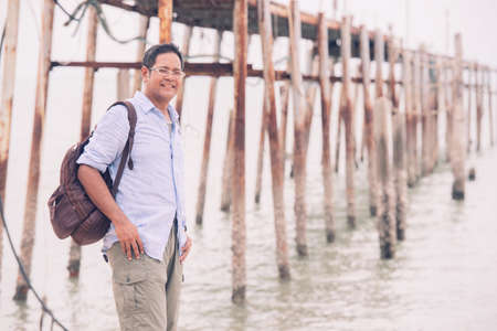 Asian male tourist standing at old wooden bridgeの写真素材