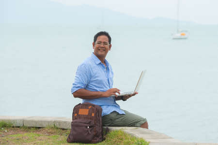 Asian traveller using computer at the beachの写真素材