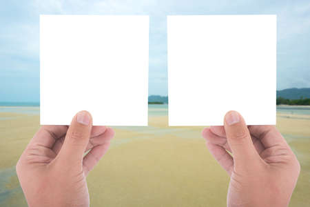 hand hold blank square paper over blur beach backgroundの写真素材