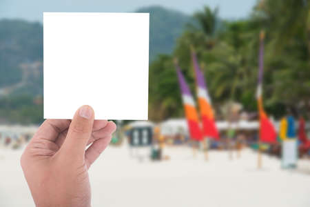hand hold blank square paper over blur beach backgroundの写真素材