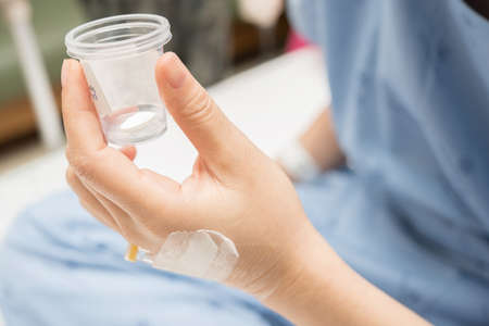 patient hold a cup contain white pillの写真素材