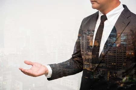 business man show hand double exposure with city lightの写真素材