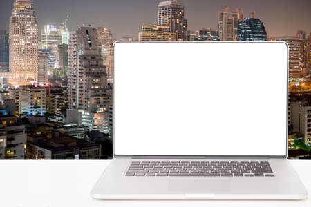 computer with blank white screen on blur building backgroundの写真素材