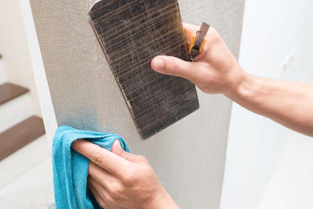 Handyman putting up wallpaper on the white wallsの写真素材