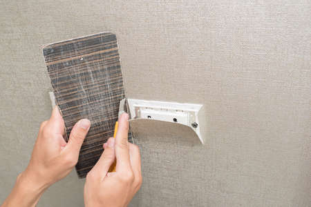 Handyman putting up wallpaper on the white wallsの写真素材