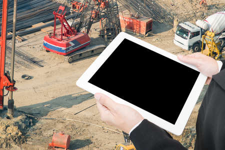 hand hold computer tablet on construction site backgroundの写真素材