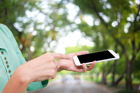 hand hold smart phone with blur green backgroundの写真素材