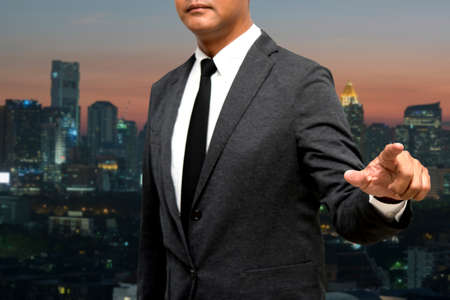 business man showing hand and finger with city light in backgroundの写真素材