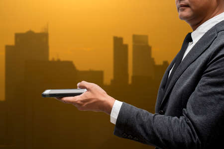 business man hold smart phone with city light in backgroundの写真素材