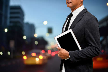 business man holding computer tablet with blur traffic background