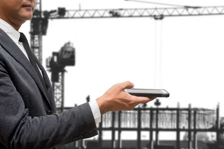business man hold smart phone with construction craneの写真素材