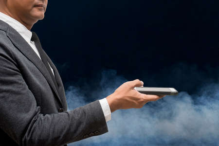 business man hold smart phone with  smokeの写真素材