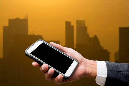 hand hold smart phone with city light in backgroundの写真素材