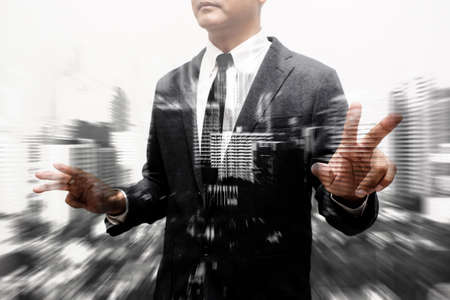 business man showing hand and finger composite with blur buildingの写真素材