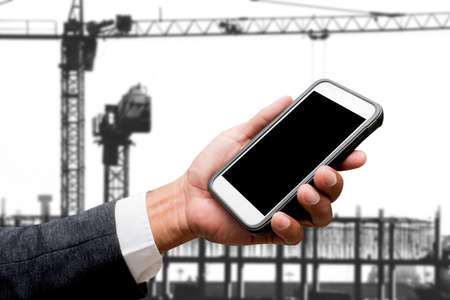 hand hold smart phone with construction craneの写真素材