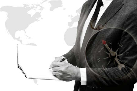 business man writing on note book with wolrd map double exposure with compass with black and white...