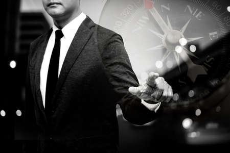 business man showing hand and finger with traffic light background double exposure with compass with black and white filterの写真素材