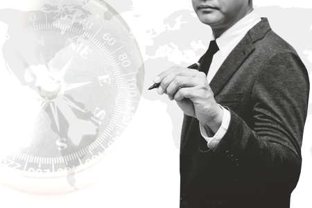 businessman holding pen with world map double exposure with compass with black and white filterの写真素材