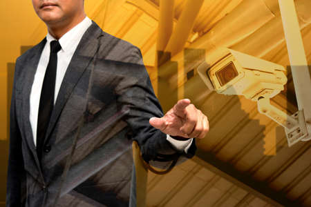 business man showing hand and finger with city light in background double exposure wtih cctv cameraの写真素材