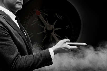 business man hold smart phone with  smoke double exposure with compass with black and white filterの写真素材