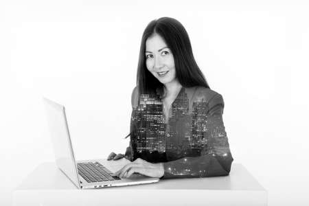 business woman using computer double exposure cith city with black and white filterの写真素材