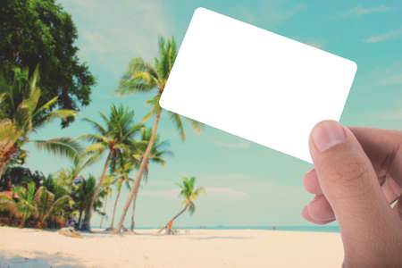 hand hold blank card on picture of coconut tree on the beach apply retro color filterの写真素材