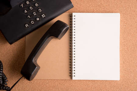 blank note book on wooden table with telephoneの写真素材