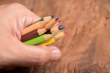 hand hold colorful pencils on wood tableの写真素材