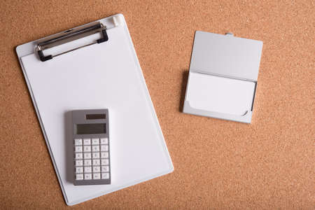 blank name card in case and clipboard with white paper on wooden table
