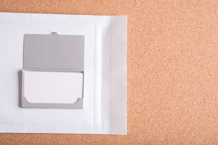blank name card in case with white envelope on wooden table