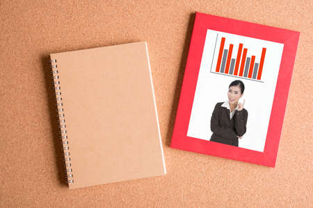 note book and  photo of business woman in frame on wooden tableの写真素材
