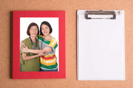 clipboard and frame with picture of mom and daughter on wooden tableの写真素材