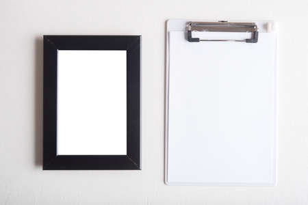 clipboard white white paper and blank black frame on white wooden tableの写真素材