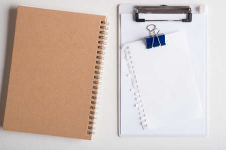 clipboard with white paper with note book on white wooden tableの写真素材