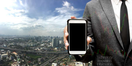 hand hold smart phone with city in backgroundの写真素材