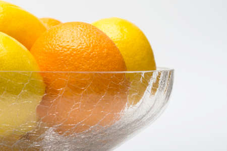 Oranges and lemons in glass bowl, high key on whiteの写真素材